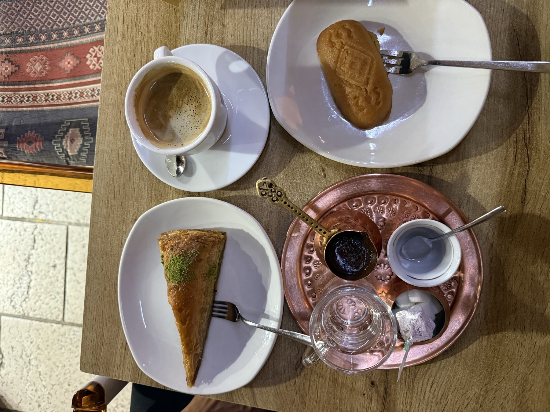 Bosnian coffee, baklava and a sweet pastry served on a copper tray and white plates